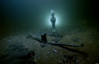 Statuette d'Osiris en bronze et barque votive en plomb posées sur les fonds sous-marin de la baie dœAboukir. Thonis-Héracléion, Égypte, VIe - IIe s. av. J.-C.. Photo : Christoph Gerigk © Franck Goddio/Hilti Foundation 